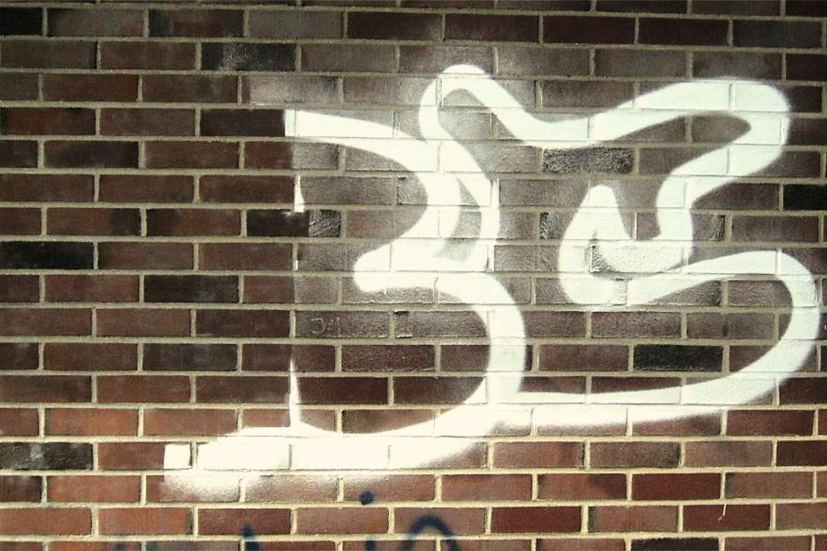 Weißes Graffiti auf einer Klinkerwand