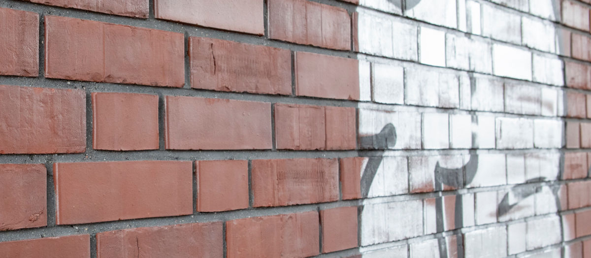 Graffiti auf einer Klinkerfassade vor der Reinigung